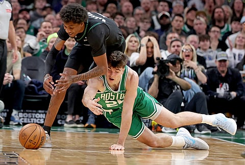 Minnesota Timberwolves forward Jaden McDaniels, left, and Boston Celtics forward Hugo González, right, trip each other up chasing the ball during the first half of an NBA basketball game, in Boston. 