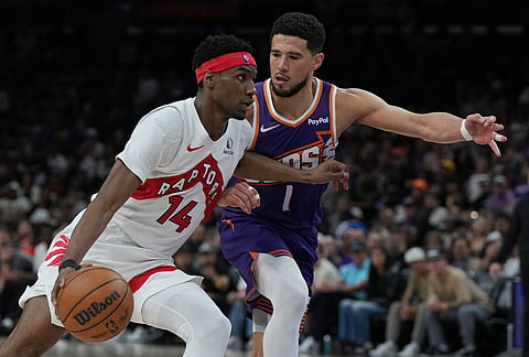 Toronto Raptors guard Ja'kobe Walter (14) drives on Phoenix Suns guard Devin Booker during the second half of an NBA basketball game in Phoenix.