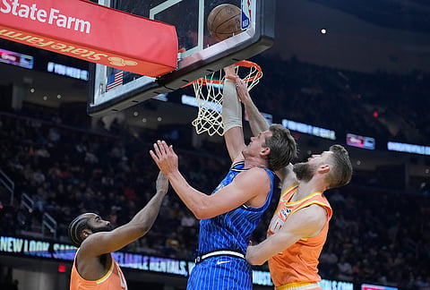 Orlando Magic forward Moritz Wagner, center, shoots between Cleveland Cavaliers guard James Harden, left, and forward Dean Wade, right, in the second half of an NBA basketball game in Cleveland.