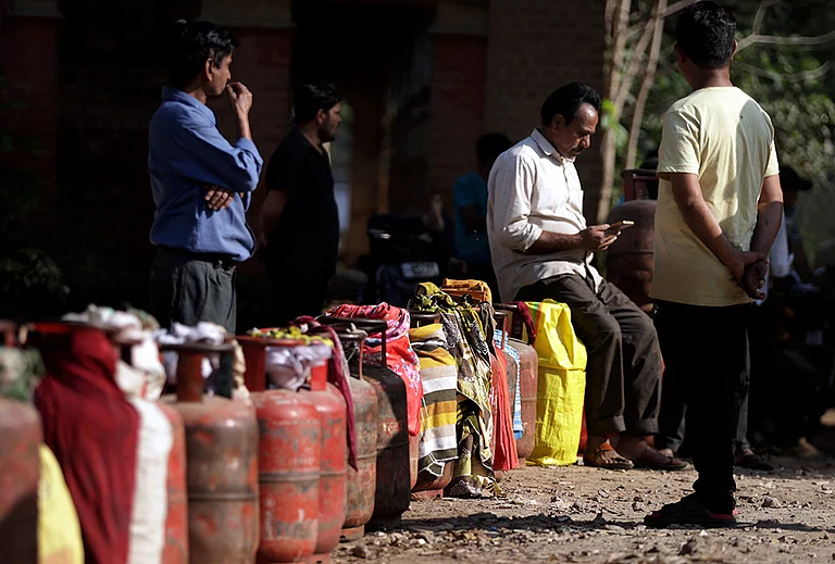 People wait in a queue with empty LPG cooking gas cylinders to avail refilled ones amid the ongoing supply crisis, in Prayagraj. - | Photo: PTI