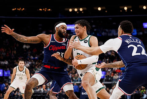 Milwaukee Bucks forward Ousmane Dieng (21) drives to the basket with the ball while being guarded by LA Clippers forward Isaiah Jackson (23) and LA Clippers guard Jordan Miller (22) during the first half of an NBA basketball game in Inglewood, California.