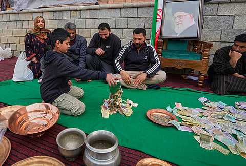 A boy empties his piggy bank to donate his savings during a relief drive for Iran in Budgam, Kashmir.