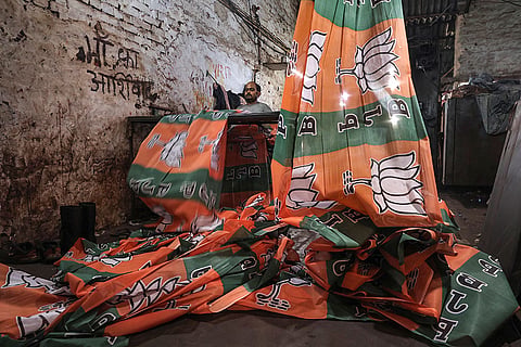A worker makes flags depicting the BJP party logo ahead of the election in various constituencies, in Mathura.