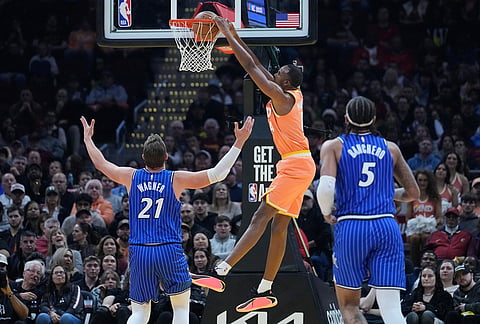 Cleveland Cavaliers center Evan Mobley, center, dunks next to Orlando Magic forward Moritz Wagner (21) in the second half of an NBA basketball game in Cleveland.