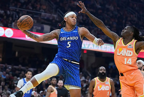 Orlando Magic forward Paolo Banchero (5) passes around Cleveland Cavaliers guard Keon Ellis (14) in the second half of an NBA basketball game in Cleveland.