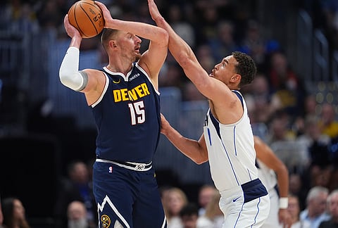 Denver Nuggets center Nikola Jokić, left, looks to pass the ball as Dallas Mavericks forward Dwight Powell defends in the first half of an NBA basketball game in Denver.