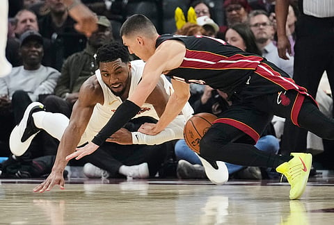Cleveland Cavaliers guard Donovan Mitchell, left, and Miami Heat guard Tyler Herro, right, dive for the ball in the second half of an NBA basketball game in Cleveland.
