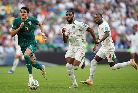Suriname's Gyrano Kerk, center, Sheraldo Becker, right, and Bolivia's Efrain Morales run for the ball during a World Cup playoff semifinal soccer match between Bolivia and Suriname in Monterrey, Mexico.