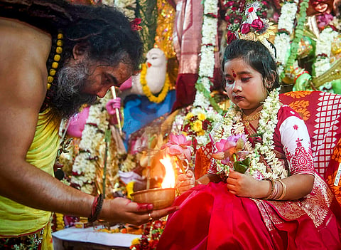 A priest seeks blessings from a young girl as part of the 'Kanya Pujan' ritual on the last day of the 'Nava Ratri' festival, at 'Dakshineswar Ramkrishna Sangha Adyapeath' temple, in Kolkata, West Bengal.