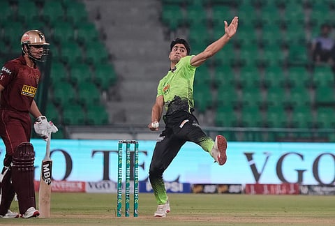 Lahore Qalandars' Ubaid Shah, right, bowls as Hyderabad Kingsmen Saim Ayub watches during the opening cricket match of the Pakistan Super League between Lahore Qalandars and Hyderabad Kingsmen, which taking place without spectators, in Lahore, Pakistan.