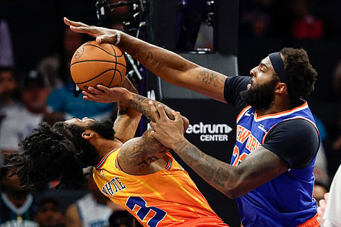 New York Knicks center Mitchell Robinson, right, blocks a shot by Charlotte Hornets guard Coby White during the first half of an NBA basketball game in Charlotte, N.C.