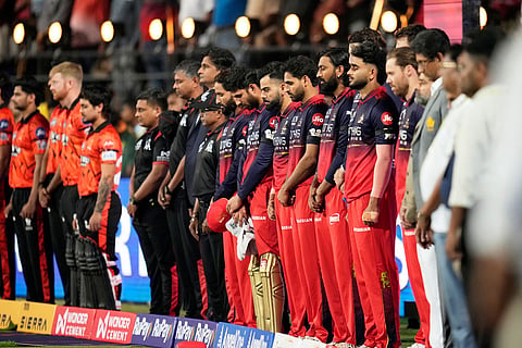 Players observe a minute's silence to pay tribute to 11 Royal Challengers Bengaluru fans who lost their lives in a stampede last year, before the start of the Indian Premier League cricket match between Royal Challengers Bengaluru and Sunrisers Hyderabad, in Bengaluru, India.