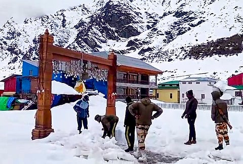 Security personnel stand guard as workers clear the snow near the 'Kedarnath Temple', in Rudraprayag district, Uttarakhand.
