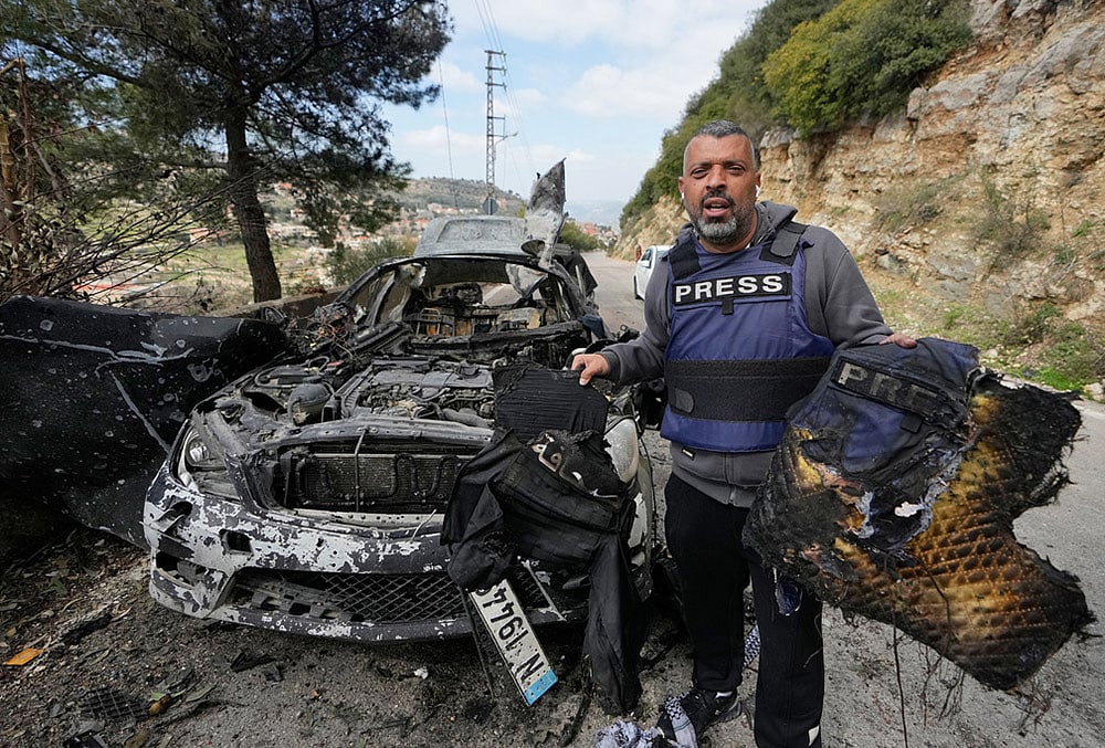 A journalist carries burned safety gear, following an Israeli airstrike on a car that killed Hezbollah's al-Manar TV correspondent Ali Shoeib, Beirut's based Al-Mayadeen TV reporter Fatima Ftouni and her brother, video journalist Mohammed Ftouni, in the town of Jezzine, south Lebanon. - | Photo: AP/Mohammed Zaatari