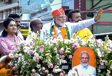 Prime Minister Narendra Modi greets supporters during a roadshow ahead of the Kerala Assembly elections, in Thrissur. Union Minister of State for Petroleum and Natural Gas Suresh Gopi is also seen. 