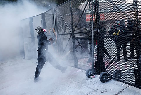 Police fire tear gas at a protestor outside the Metropolitan Detention Center in downtown Los Angeles during a "No Kings" rally.