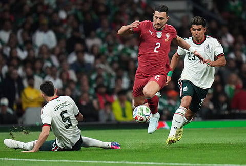 Portugal's Diogo Dalot, center, controls he ball against Mexico's Johan Vasquez, left, and Jesus Gallardo during the international friendly soccer match between Mexico and Portugal in Mexico City.