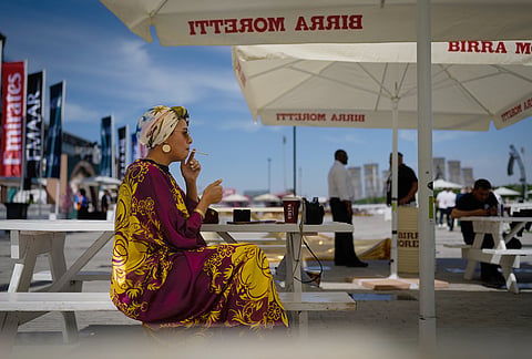 A racegoer smokes a cigarette at Meydan Racecourse ahead of the Dubai World Cup, United Arab Emirates.