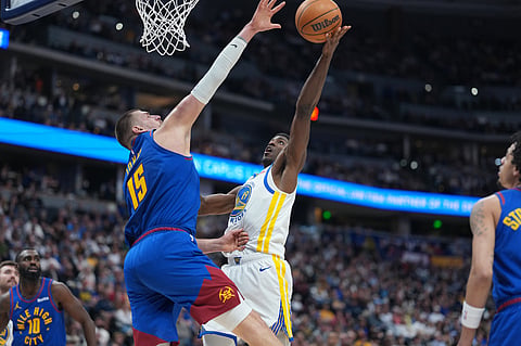 Golden State Warriors guard Nate Williams, right, goes up for a basket as Denver Nuggets center Nikola Jokić defends in the second half of an NBA basketball game in Denver.