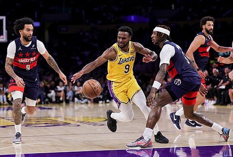 Los Angeles Lakers guard Bronny James, center, drives against Washington Wizards guard Jamir Watkins, right, and forward Justin Champagnie during the second half of an NBA basketball game in Los Angeles.