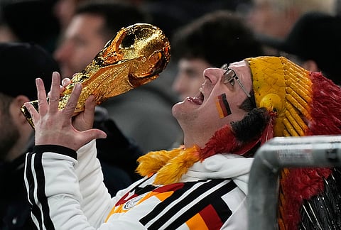 A German supporter reacts on the tribune with a copy of the World Cup trophy during an international friendly soccer match between Germany and Ghana in Stuttgart, Germany.