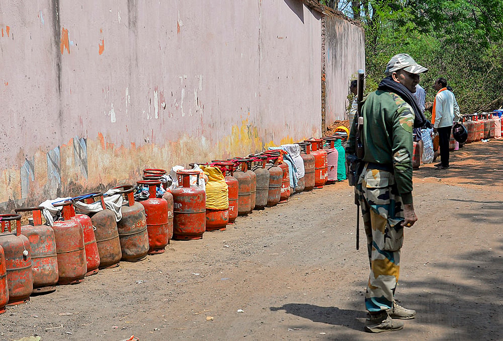 A security personnel stands guard as empty LPG cylinders are arranged in a line amid an ongoing supply crisis, in Ranchi, Jharkhand. - | Photo: PTI