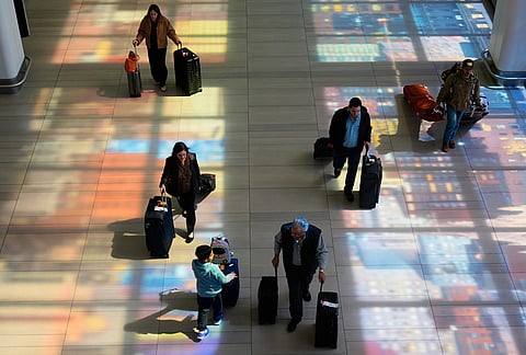 Stained-glass windows cast colorful shadows on the floor as travelers walk through LaGuardia Airport in New York.