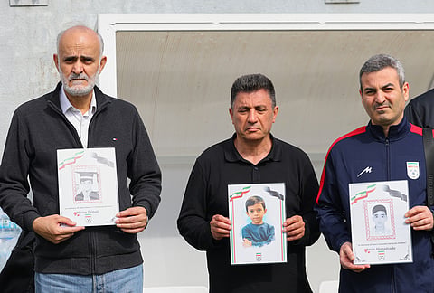 Iran's coach Amir Ghalenoei, center, and Iran's Football Federation Vice President Mehdi Mohammad Nabi, left, hold pictures of children allegedly killed in a U.S. and Israel strikes in Iran, before a friendly soccer match between Iran and Costa Rica, in Antalya, southern Turkey.