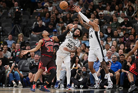 Chicago Bulls guard Isaac Okoro (35) tangles with San Antonio Spurs' Julian Champagnie (30) and Devin Vassell (24) during the first half of an NBA basketball game, in San Antonio.