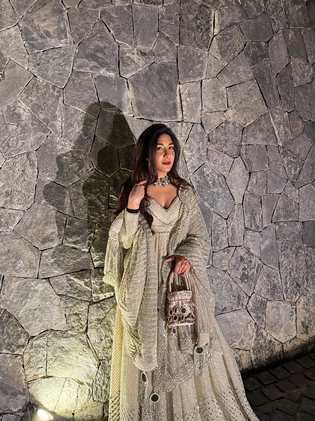 Harmann in a beige lehenga by a rustic stone wall - null