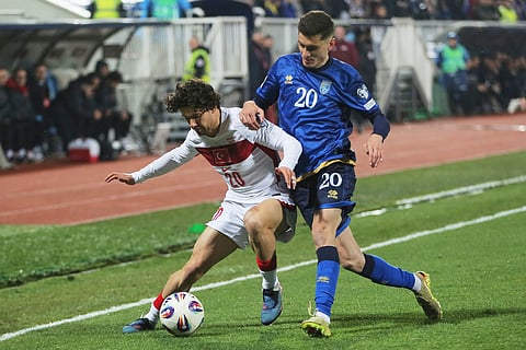 Turkey's Ferdi Kadioglu and Kosovo's Veldin Hodza challenge for the ball during the World Cup qualifying playoff final.