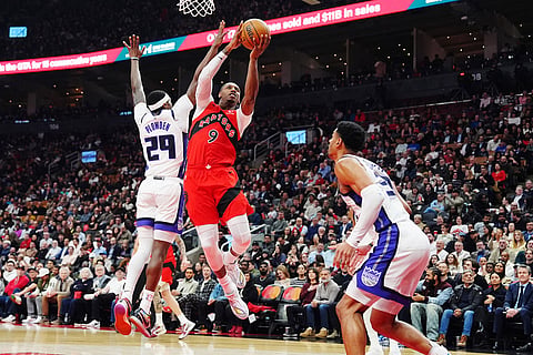 Toronto Raptors' RJ Barrett (9) leaps past Sacramento Kings' Daeqwon Plowden (29) as Dylan Cardwell (32) defends during the first half of an NBA basketball game in Toronto.