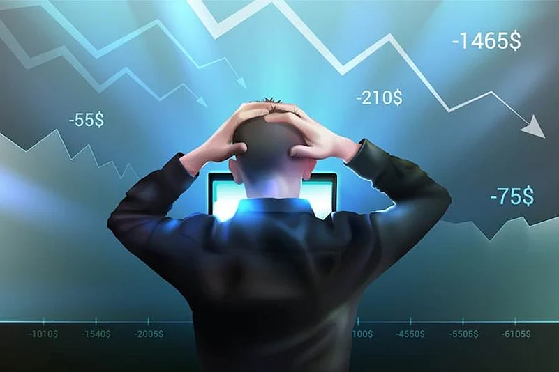 Person holding their head while watching falling market losses on screen