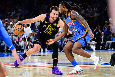 Los Angeles Lakers forward/guard Luka Dončić (77) drives against Oklahoma City Thunder guard Cason Wallace (22) during the first half of an NBA basketball game in Oklahoma City. 