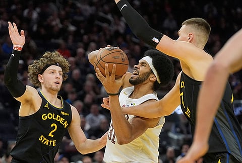 Cleveland Cavaliers center Jarrett Allen, middle, drives to the basket against Golden State Warriors guard Brandin Podziemski (2) and center Kristaps Porzingis during the second half of an NBA basketball game in San Francisco.