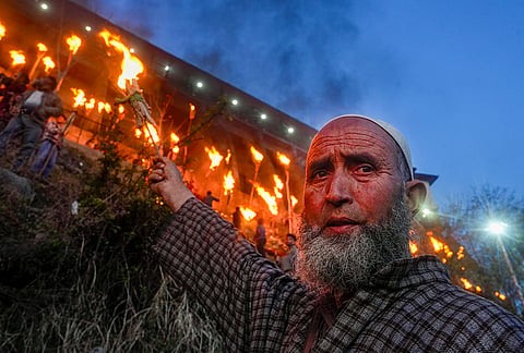 A devotee raises a lit flambeau during the old torch festival in Kashmir, known as Zool or Frow, on Aishmuqam hills, near the Shrine of Hazrat Zain-ud-Din Wali, in Anantnag.