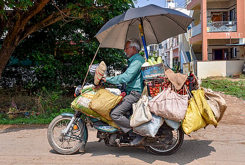 A vendor carries vegetables on a bike on a summer day, in Chikkamagaluru, Karnataka.
