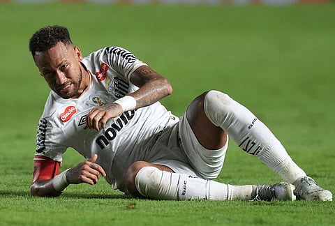 Santos' Neymar sits on the pitch after he was fouled during a Brazilian soccer league match against Remo in Santos, Brazil.