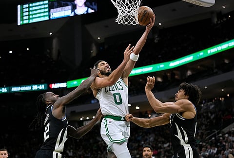 Boston Celtics' Jayson Tatum (0) shoots between Milwaukee Bucks' Taurean Prince and Jericho Sims during the second half of an NBA basketball game in Milwaukee. 