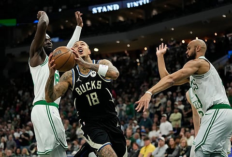 Milwaukee Bucks' Kyle Kuzma (18) drives to the basket between Boston Celtics' Derrick White, right, and Neemias Queta, left, during the first half of an NBA basketball game in Milwaukee. 