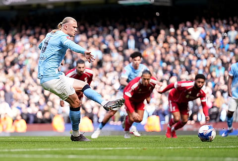 Manchester City's Erling Haaland scores their side's first goal of the game from a penalty during the FA Cup quarter-final soccer match between Manchester City and Liverpool in Manchester, England.