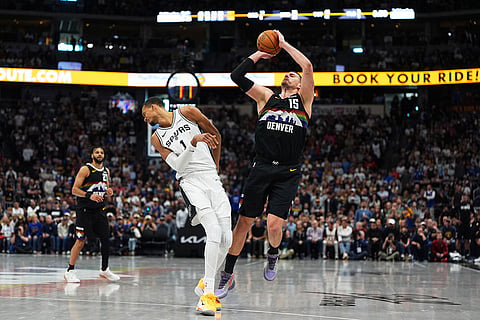 San Antonio Spurs center Victor Wembanyama, left, reels back after getting hit by Denver Nuggets center Nikola Jokic as he went up for a shot in overtime of an NBA basketball game in Denver.