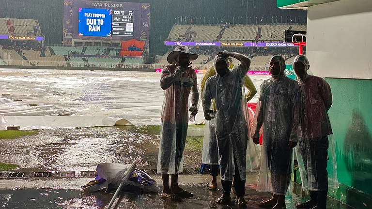 Ground staff stand on covers as it rains during the Indian Premier League match between Kolkata Knight Riders and Punjab Kings in Kolkata. - AP