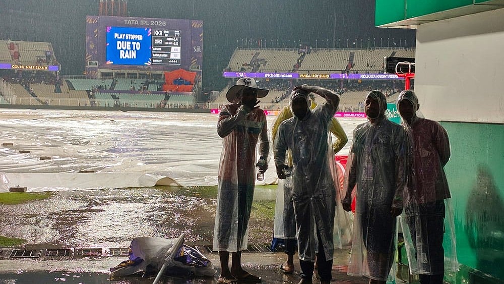 Ground staff stand on rain covers as it rains during the Indian Premier League cricket match between Kolkata Knight Riders and Punjab Kings in Kolkata. - | Photo: AP/Bikas Das