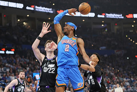 Oklahoma City Thunder guard Shai Gilgeous-Alexander (2) passes the ball over Utah Jazz forward Kyle Filipowski (22) and guard Ace Bailey (19) during the first half of an NBA basketball game in Oklahoma City. 