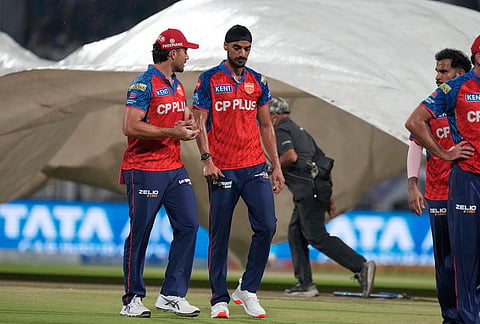 Punjab Kings' Arshdeep Singh and others leave the field as ground staff pull in rain covers as it rains during the Indian Premier League cricket match between Kolkata Knight Riders and Punjab Kings in Kolkata.