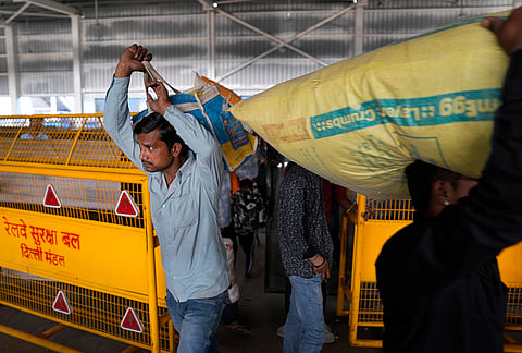 Carrying sacks of goods on their shoulders, labourers at the New Delhi Railway yard push through the strain.