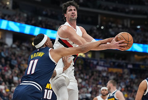 Portland Trail Blazers forward Deni Avdija, right, goes up for a basket as Denver Nuggets guard Bruce Brown defends in the first half of an NBA basketball game, in Denver. 