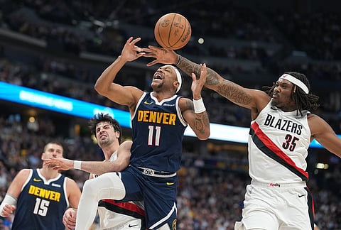 Portland Trail Blazers center Robert Williams III, right, fouls Denver Nuggets guard Bruce Brown, center, as Portland forward Deni Avdija defends in the second half of an NBA basketball game in Denver.