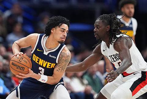 Denver Nuggets guard Julian Strawther, left, looks to pass the ball as Portland Trail Blazers guard Jrue Holiday defends in the first half of an NBA basketball game, in Denver.